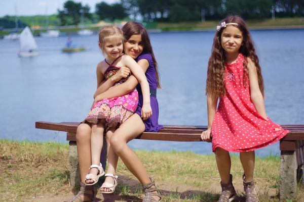 Crianças sentadas no banco perto do lago . — Fotografia de Stock