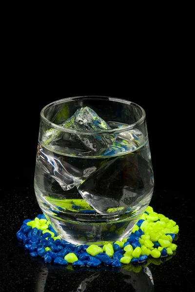 Стекло со льдом и водой на гравии — стоковое фото