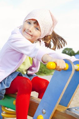 Girl playing on children's playground clipart