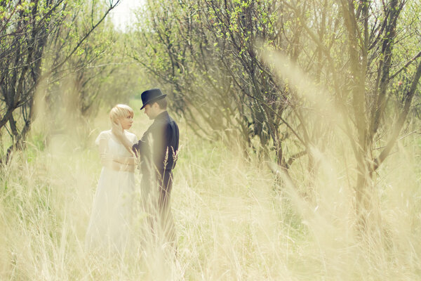 Молодая пара, молодожены, одеты в стиле ретро, в саду
