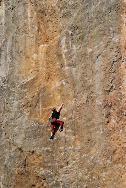 Homem alpinista em uma parede de rocha — Fotografia de Stock