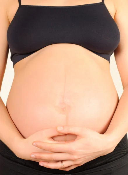 Gravid kvinna omfamnar magen — Stockfoto