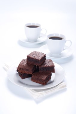 Beyaz tabak ve iki bardak kahve çikolatalı kek
