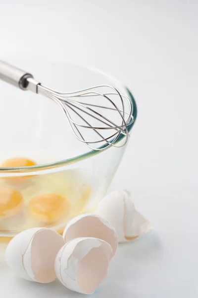 Whisk with eggs in a bowl — Stock Photo, Image
