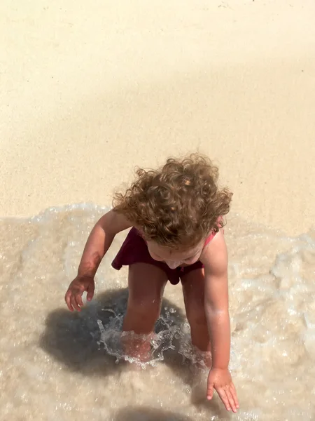 En liten flicka som leker i vågorna — Stockfoto