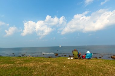 Retired couple relaxing and admiring the coastal scenery. clipart