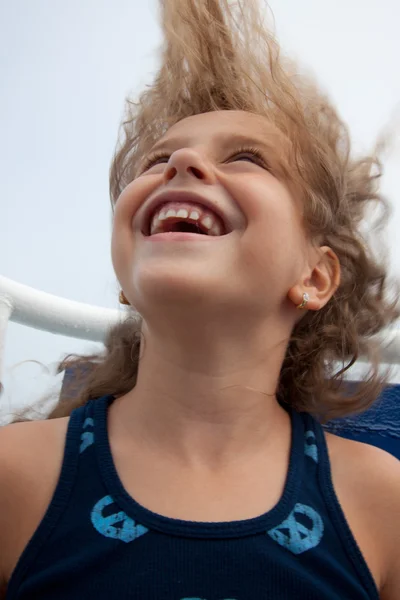 Petite fille mignonne riant avec ses cheveux soufflés dans le vent . — Photo