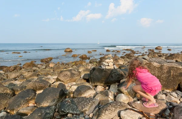 Hübsches kleines Mädchen kriecht Felsen an der felsigen Küste. — Stockfoto