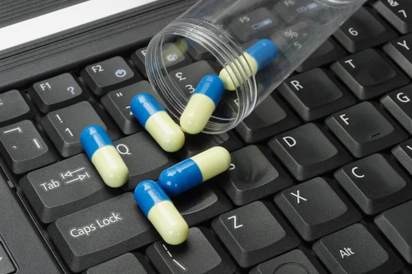 Tabletták ömlött a fekete laptop billentyűzet — Stock Fotó