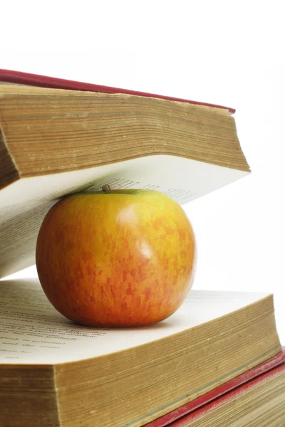 Červené jablko a staré knihy — Stock fotografie