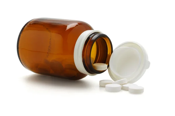Open glass bottle and spliied tablets — Stock Photo, Image