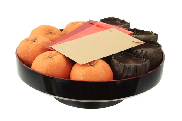 Китайский новогодний рисовый торт, мандаринские апельсины и красные пакеты — стоковое фото