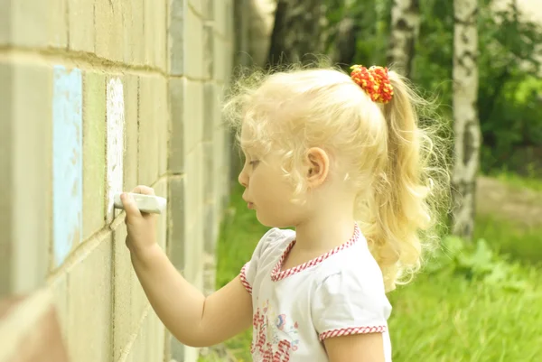 小女孩在墙上用粉笔绘制 图库图片