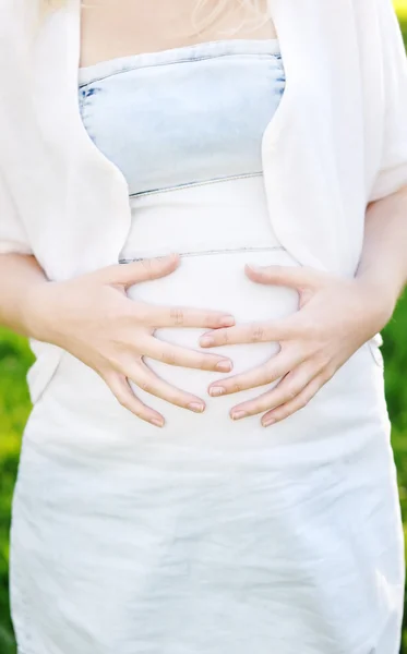 Žena drží za ruce na její těhotné břicho — Stock fotografie