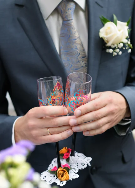 Groom is holding painting glasses — Stock Photo, Image
