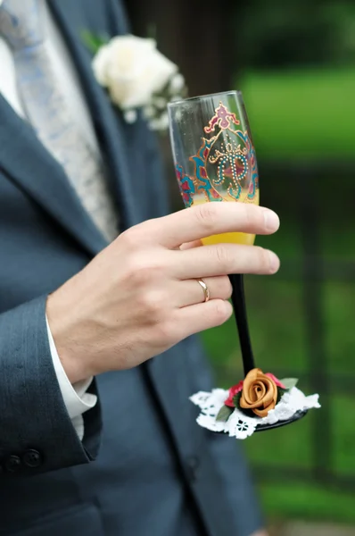 Groom is holding painting champagne glasses — Stock Photo, Image