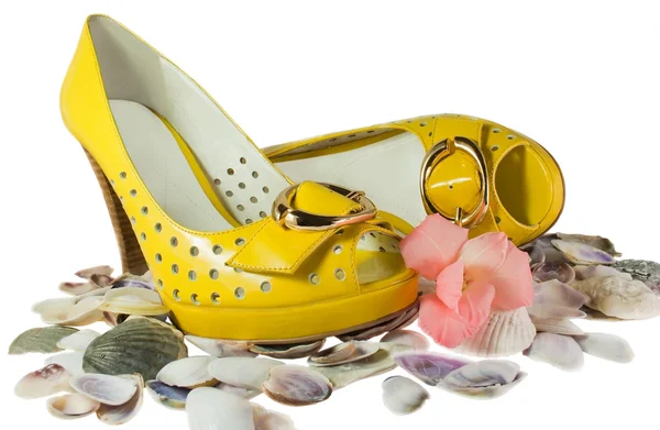 Пара желтых ботинок и ракушек, изолированных на белом — стоковое фото