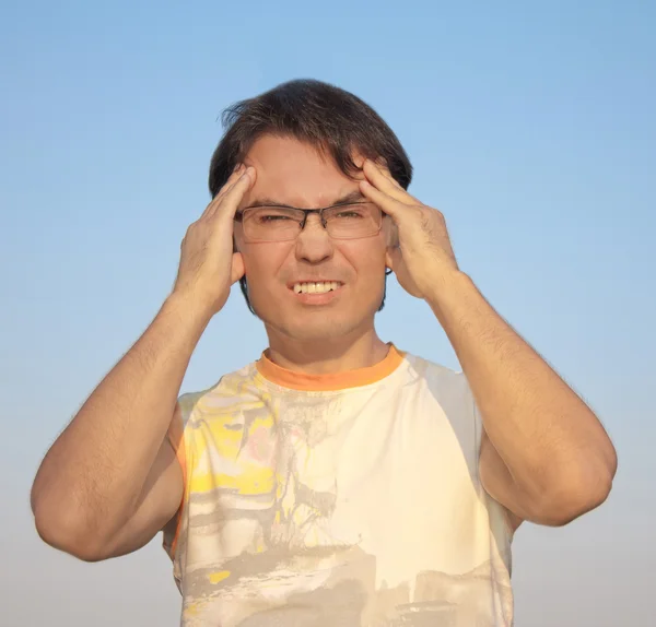 Jonge man met een hoofdpijn tegen blauwe hemel — Stockfoto