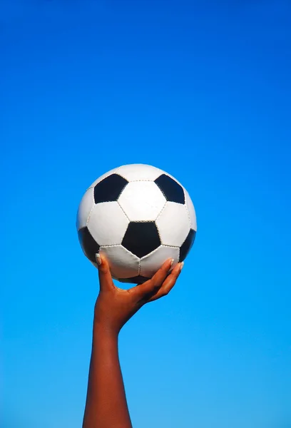 Bola de futebol na mão preta — Fotografia de Stock