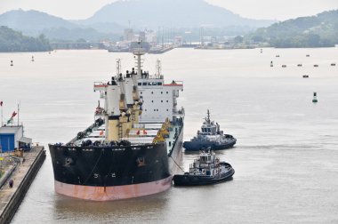 Tugboats pushing ship in the Panama Channel clipart