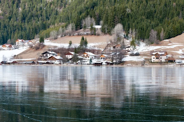 Dorf am zugefrorenen Bergsee — Stockfoto