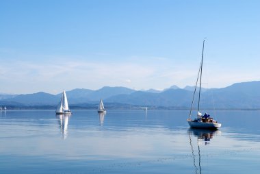 Sailing boats in sunny peaceful lake clipart