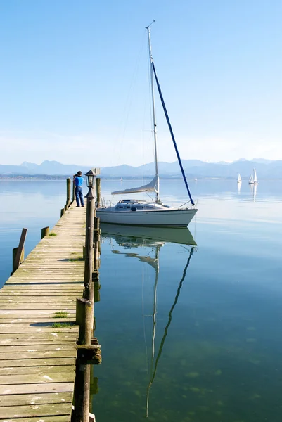 stock image Sailing boat and reflection in peaceful lake pier