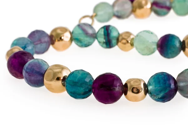 Beads from multi-coloured stones and gold on a white background — Stock Photo, Image