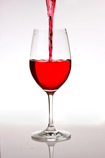 Jet de vin rouge courant dans un verre — Photo
