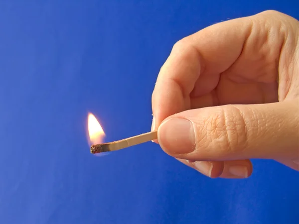 En hand som håller en eldade matchstick — Stockfoto