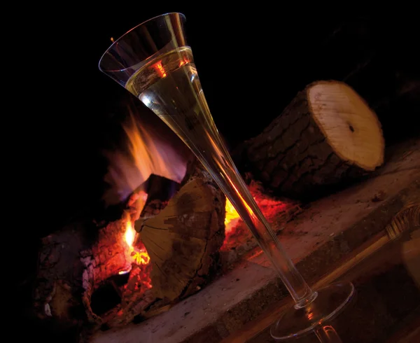 Una tazza di champagne vicino al camino, a casa in inverno. Bancomat caldo e romantico — Foto Stock