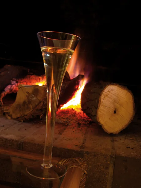 Uma chávena de champanhe perto da lareira, em casa no inverno. Caixa eletrônico quente e romântico — Fotografia de Stock