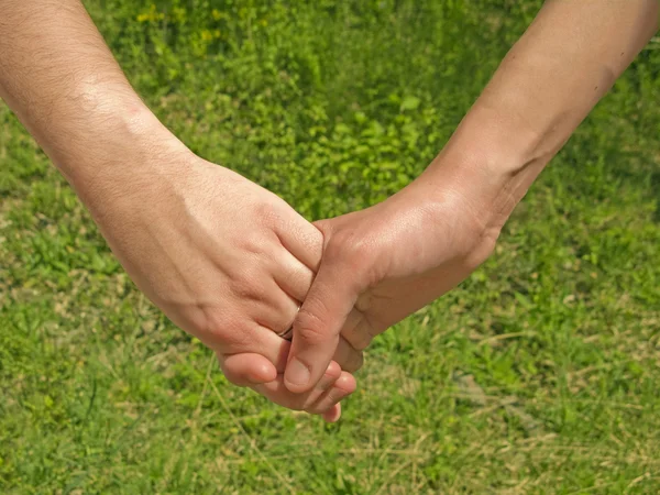 stock image Two hands over green nature background. Love and friendship concept