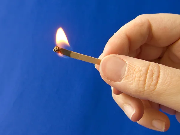 A hand holding a fired matchstick Stock Picture