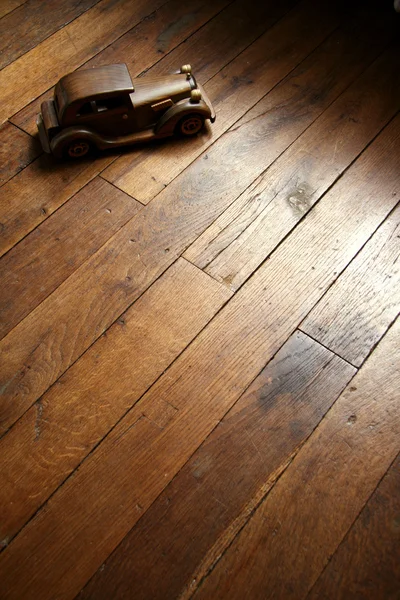 寄せ木細工の床でレトロな木造車モデル ロイヤリティフリーのストック写真