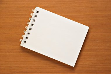 Wire-o notepad on wooden desk background clipart