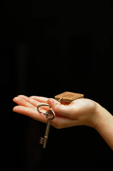 Протянутая рука с ключом от дома — стоковое фото