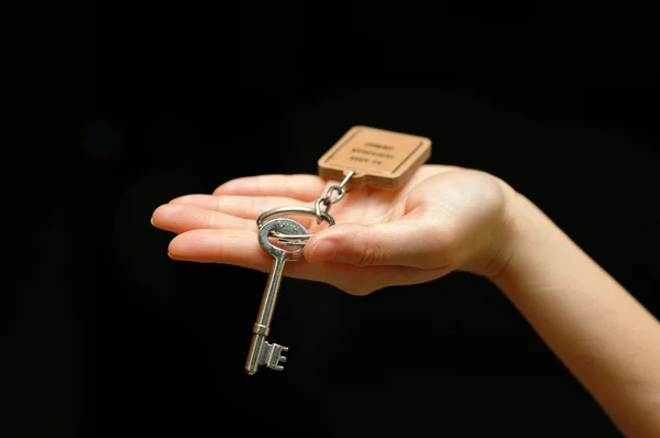 Outstretched hand holding a house key — Stock Photo, Image