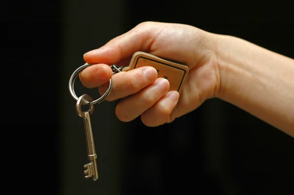 Main tendue tenant une clé de la maison — Photo