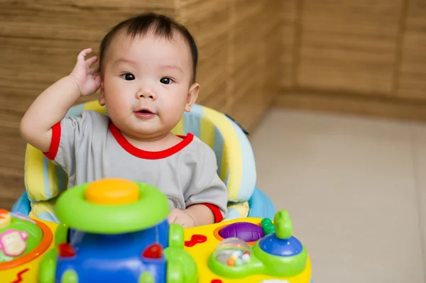 6 month old Asian baby girl plays sitting in a walker — Stock Photo, Image