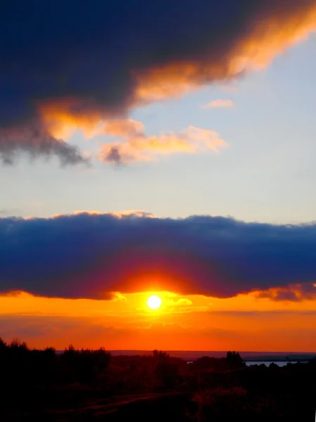 Pôr-do-sol vermelho brilhante com uma nuvem escura — Fotografia de Stock