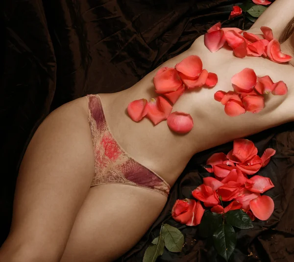 Frau mit Rosenblättern bedeckt — Stockfoto