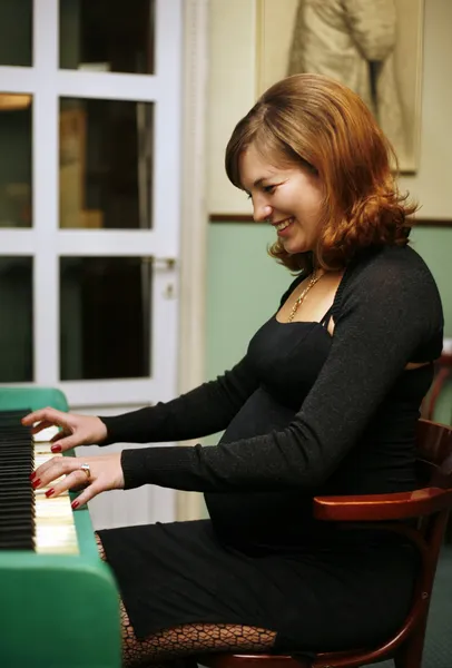 Hamile kadın üzerinde piyano çalıyor. — Stok fotoğraf