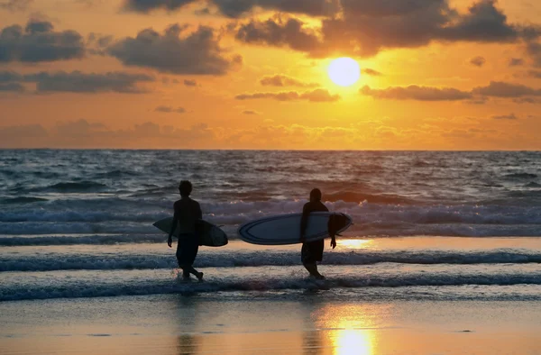 Серфингисты на красном закате — стоковое фото