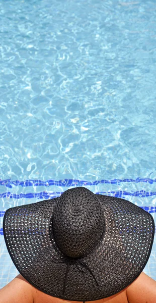 Mujeres con pamela en una posición relajada en la piscina — Foto de Stock