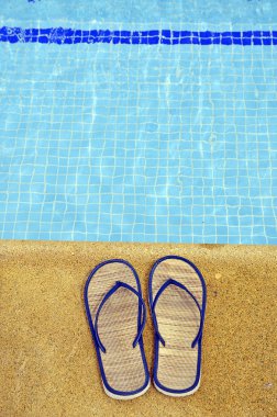 Women's flip flops on the feet of the pool clipart