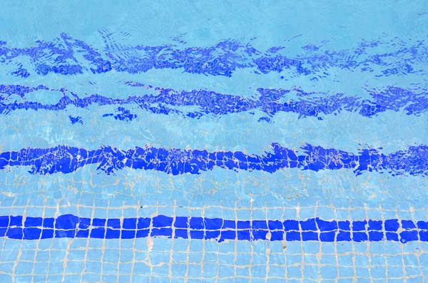 Escaleras de azulejos en el agua azul de la piscina — Foto de Stock