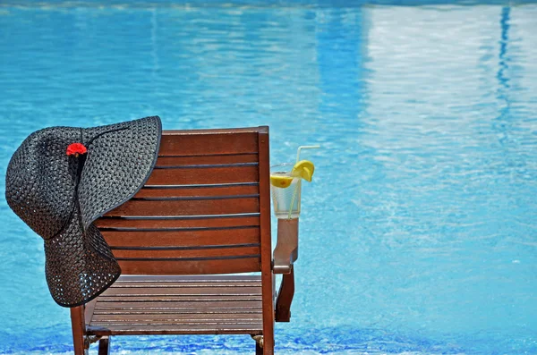 Silla de madera con sombrero y limonada junto a la piscina —  Fotos de Stock
