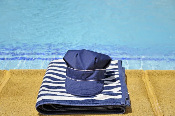 Cappello da pesca e asciugamano a righe in piscina — Foto Stock