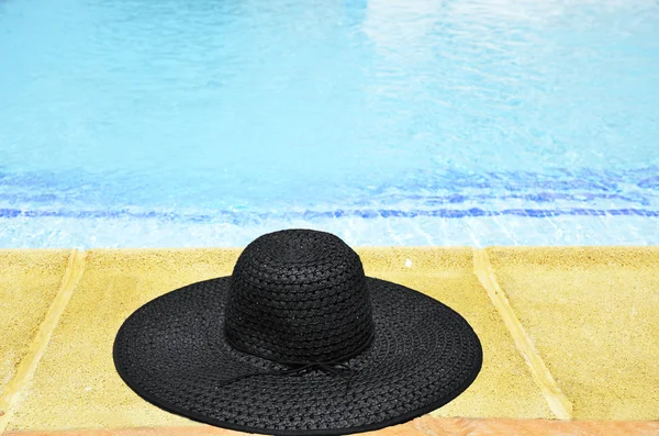 Vrouw hoed aan de voet van het zwembad — Stockfoto